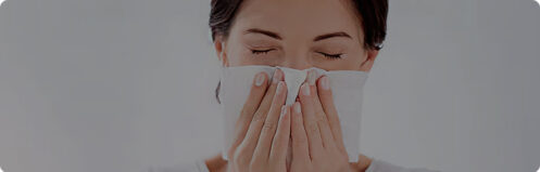 Woman sneezing blowing her nose into a tissue