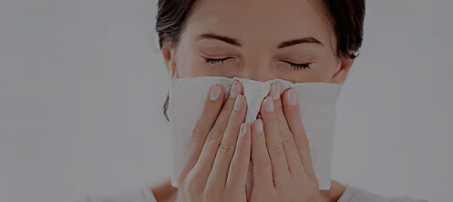 Woman sneezing blowing her nose into a tissue