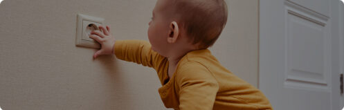 Baby sticking it's hand in a babyproofed electrical socket