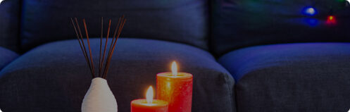 Couch with colorful Christmas lights behind a table with pretty festive candles