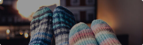Close up of feet in colorful fuzzy socks propped up in front of a TV